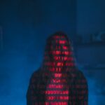 Sylwetka w ciemności z czerwonym kodem binarnym na twarzy