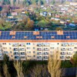 Osiedle bloków z panelami słonecznymi na dachach z lotu ptaka