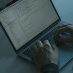 Programista pisze kod na laptopie, dbając o bezpieczeństwo łańcucha dostaw