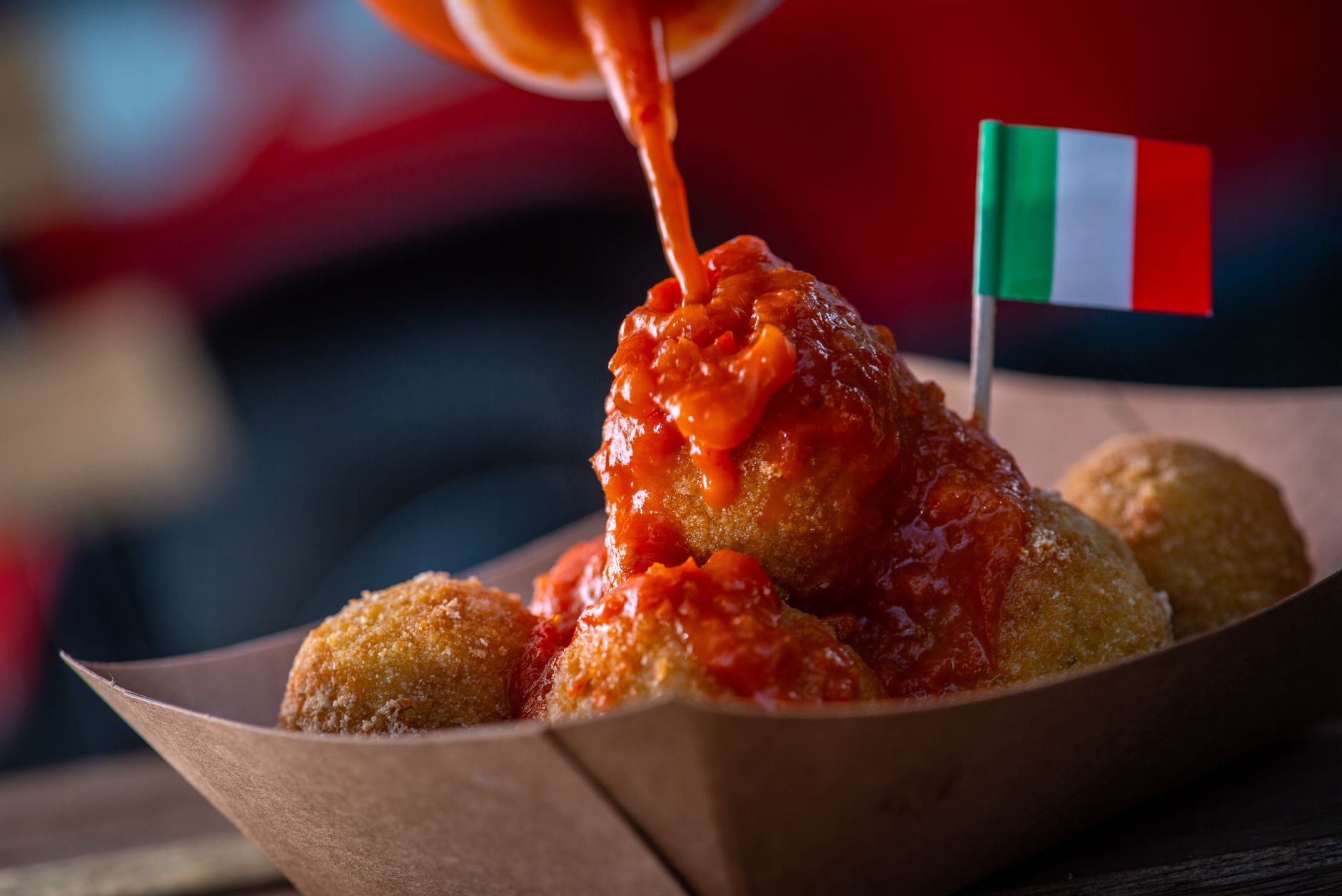 Arancini z sosem pomidorowym z małą flagą Włoch z bliska