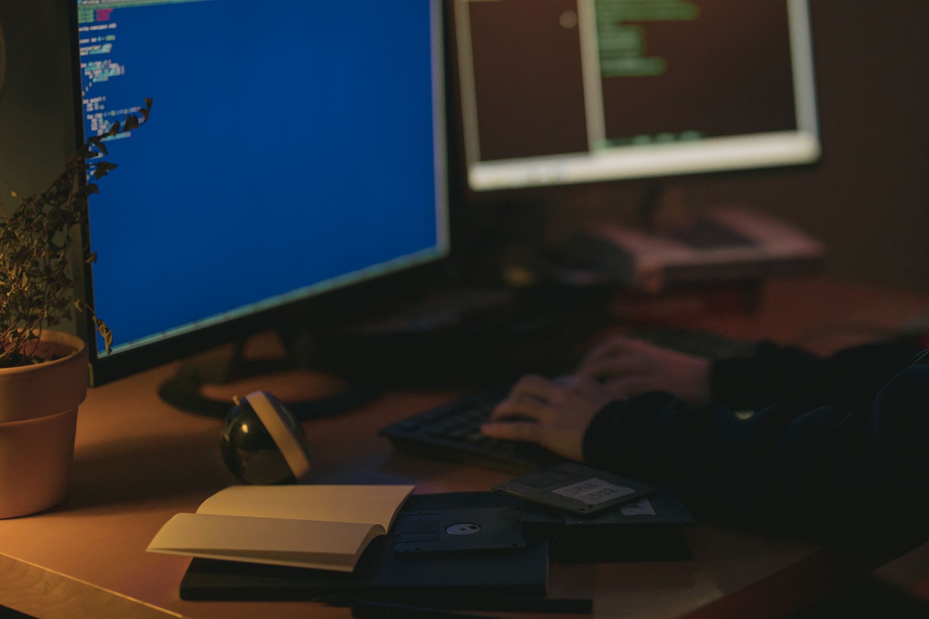 Programista przy dwóch monitorach w przyciemnionym pokoju