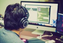 Programista w słuchawkach przy komputerze z dwoma monitorami
